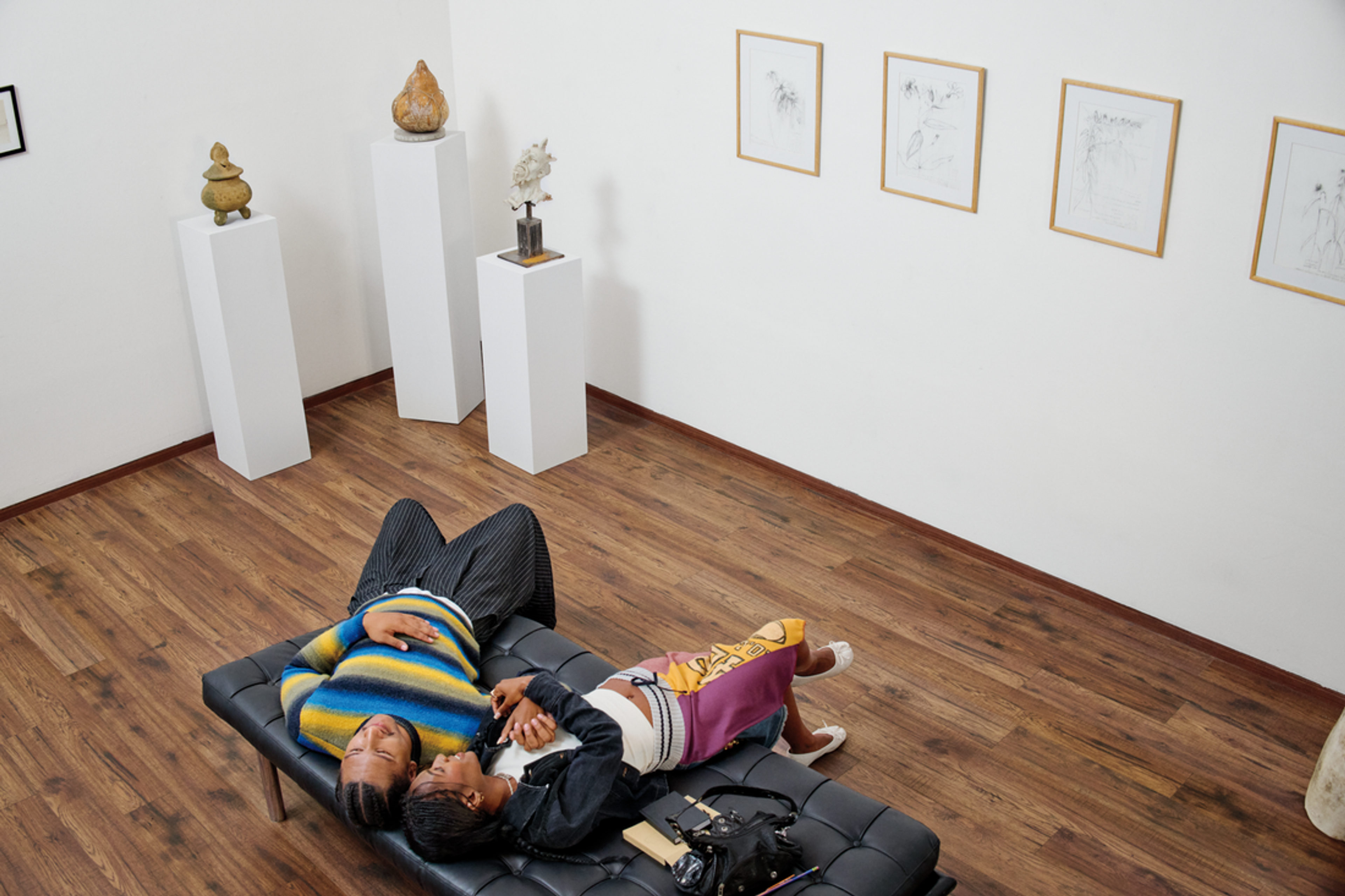 A couple lays on a bench at a museum, their heads leaning towards each other