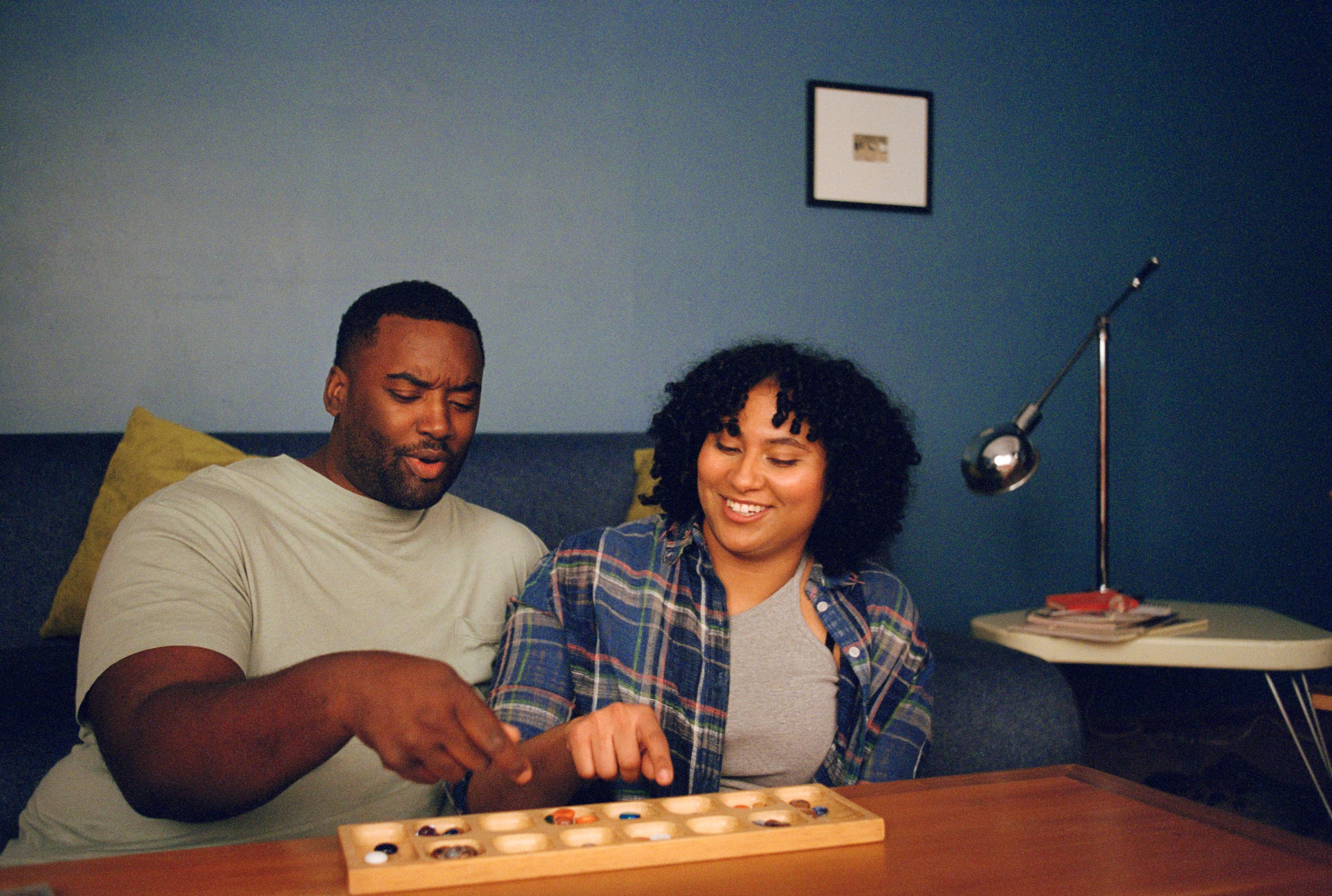 Two people enjoying themselves playing mancala.